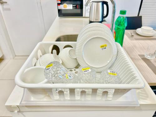 ein Tablett mit Tellern, Tassen und Geschirr in einem Waschbecken in der Unterkunft Comfort Place 1-8 Pax 3Q beds Ara Damansara Center in Petaling Jaya
