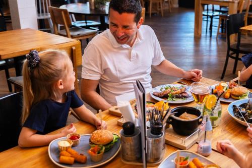 a man and a little girl sitting at a table with food at Summio Parc Port Greve in Brouwershaven