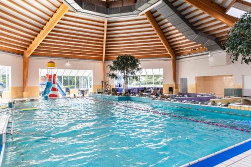 een groot zwembad in een groot gebouw met een groot plafond bij Summio Parc Port Greve in Brouwershaven