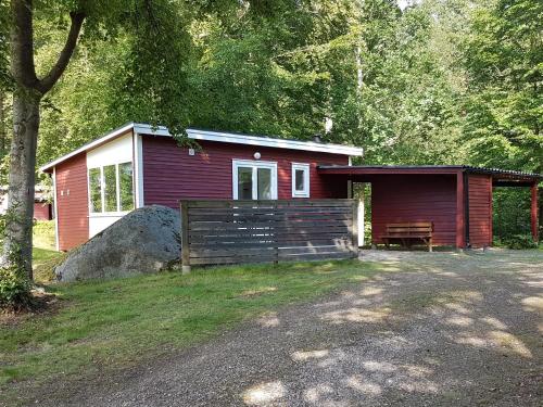 a small red cabin with a bench in front of it at Långasjönäs Camping & Stugby in Karlshamn
