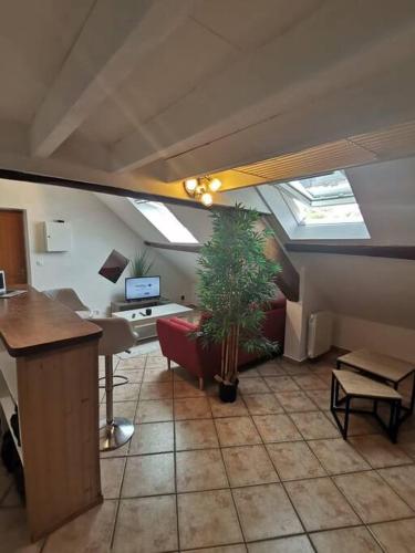 Cette chambre mansardée comprend un bureau et une plante en pot. dans l'établissement Appartement cozy avec mezzanine, à Souppes-sur-Loing