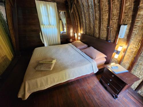 a bedroom with a large bed and a wooden floor at Timbis Homestay Bali in Nusa Dua