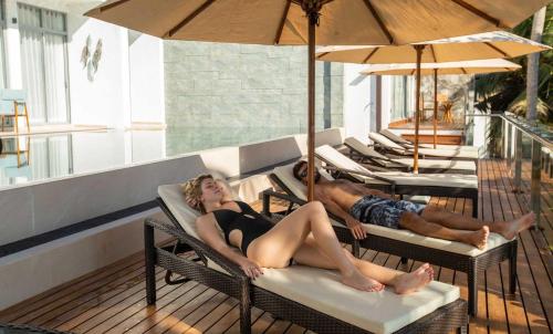 a man and a woman laying on chairs on a patio at Beacon By The Bay Villas and Suites by the Clarks in Matara