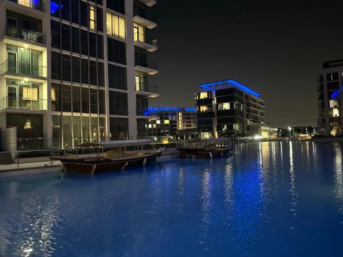 een groep gebouwen met boten in het water 's nachts bij Oraya - Skyline Serenity at 1BR in District One in Dubai