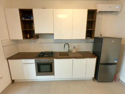 uma cozinha com armários brancos e um frigorífico de aço inoxidável em Apartment Romana - next to the sea em Novalja