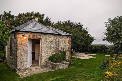 a small brick building in a grassy yard at The Lookout: Cosy Compact Cottage in Totland