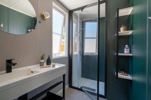 ein Bad mit einem Waschbecken und einer Glasdusche in der Unterkunft Camping Le Bois Fleuri in Argelès-sur-Mer