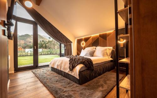 - une chambre avec un grand lit et une grande fenêtre dans l'établissement Luxury Aframe, à Râșnov