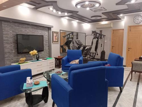 a living room with blue chairs and a tv at White Lotus Karachi in Karachi