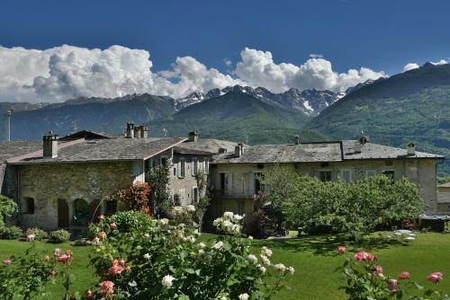 an old stone house with mountains in the background at La Rosa al Roseto del Drago in Ponte in Valtellina