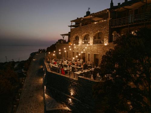 a crowd of people sitting outside of a building at night at Aegean Castle Andros – Adults Only in Agia Eleousa