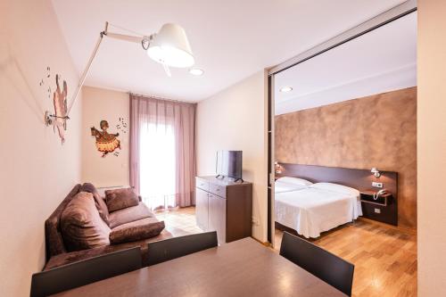 een woonkamer met een bank en een bed bij Hotel La Perla D'Olot in Olot