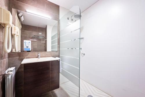 uma casa de banho com um lavatório e uma cabina de duche em vidro. em Hotel La Perla D'Olot em Olot