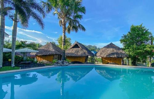 un complexe avec une piscine et quelques cabanes dans l'établissement Casa Basilisa Eco-Boutique Resort by Cocotel, à Guinobatan