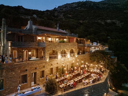 un edificio con un grupo de personas sentadas fuera por la noche en Aegean Castle Andros – Adults Only, en Agia Eleousa