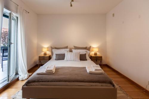 a bedroom with a large bed and a large window at FLH Restelo Duplex with Garden & Parking in Lisbon