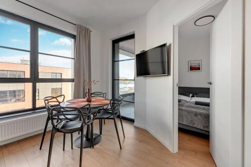 a dining room with a table and chairs and a bedroom at DOKI Living & Foodhall Apartament in Gdańsk