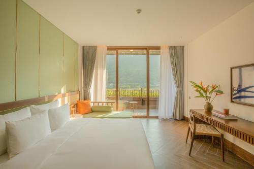 a bedroom with a large bed and a desk with a desk at Mandala Retreats Kim Bôi in Hòa Bình