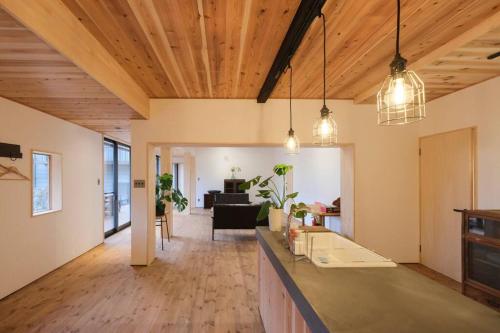 a living room with wood ceilings and a kitchen with pendant lights at プラベート薪サウナ付 1日1組限定ease1高山村 in Takayama