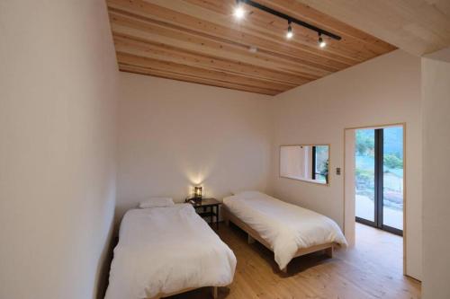 2 bedden in een kamer met houten plafonds bij プラベート薪サウナ付 1日1組限定ease1高山村 in Takayama