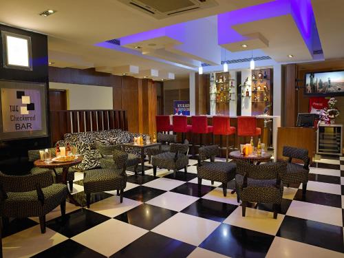 un restaurante con mesas y sillas en un suelo a cuadros en MGM Mark Whitefield, en Bangalore