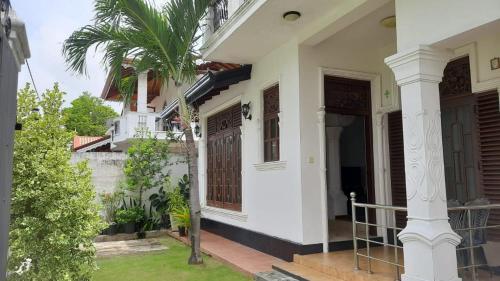 een wit huis met een poort en een palmboom bij Party Allowed luxury 4 roomed Furnished house in Jaela in Ja-Ela