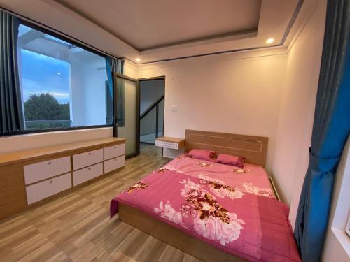 een slaapkamer met een bed en een groot raam bij Căn hộ S'pung Villa in Bao Loc