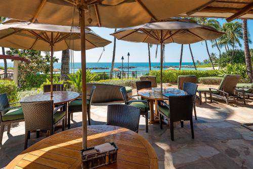 an outdoor patio with tables and chairs and umbrellas at Ko Olina Beach Villas O1404 in Kapolei