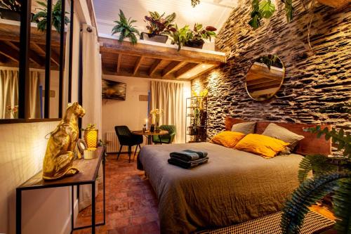 a bedroom with a bed and a stone wall at Love Room Bohème Les Petits Plaisirs in Angers