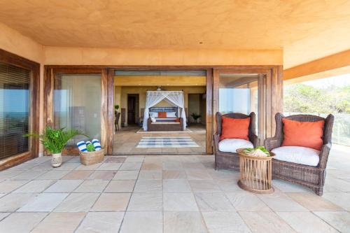 a screened in porch with two chairs and a fireplace at Collection Luxury Accommodation: Quinta Do Sol, Vilanculos, Mozambique in Vilanculos