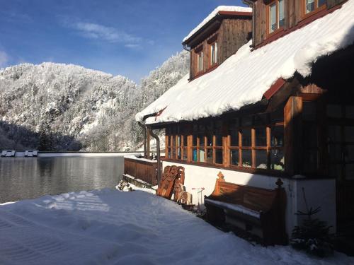 a building covered in snow next to a lake at Chata Motyčky in Donovaly