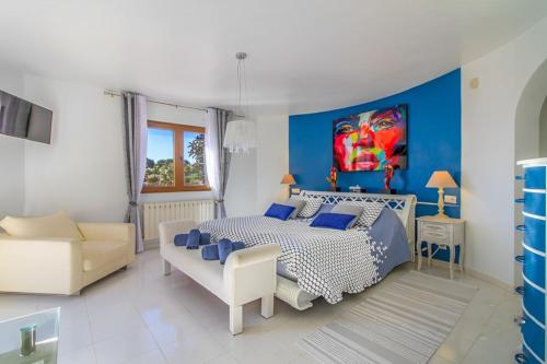 Dormitorio azul y blanco con cama y sofá en Fustera Villa El Salvador, en Benissa