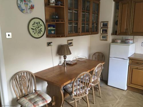 a kitchen with a wooden table with chairs and a refrigerator at South Side in West Runton