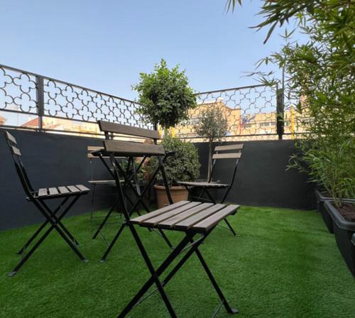 a picnic table and two chairs sitting on the grass at Hostel Faro Málaga modern & luxury in Málaga