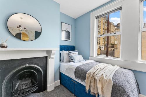 a bedroom with blue walls and a bed with a fireplace at Charming House in Bath - Sleeps 11 in Bath