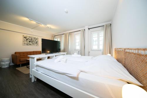 a bedroom with a large white bed and a television at Favorite Stays -Suite and More - Altstadt in Düsseldorf