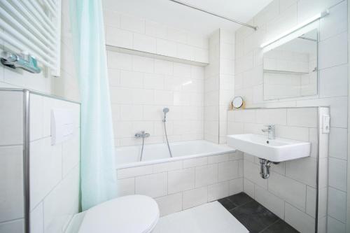 a white bathroom with a sink and a bath tub at Favorite Stays -Suite and More - Altstadt in Düsseldorf