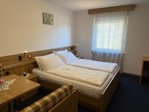 a bedroom with a bed and a table and a window at PANORAMA SportHOTEL in Folgaria