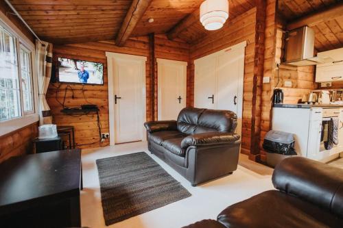 a living room with a leather chair and a couch at Rustic Log Cabin in Snowdonia - 2 Bedrooms & Parking in Ffestiniog