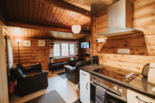 a kitchen with a stove and chairs in a cabin at Rustic Log Cabin in Snowdonia - 2 Bedrooms & Parking in Ffestiniog