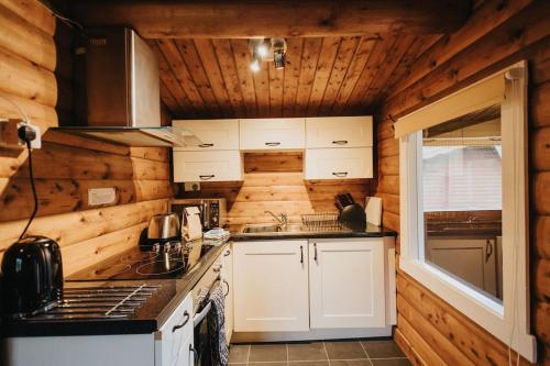 a kitchen with white cabinets and a stove top oven at Rustic Log Cabin in Snowdonia - 2 Bedrooms & Parking in Ffestiniog