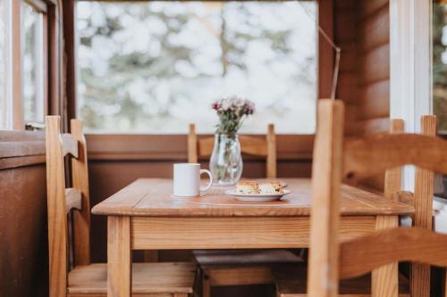 a wooden table with a vase of flowers and a table and chairs at Rustic Log Cabin in Snowdonia - 2 Bedrooms & Parking in Ffestiniog