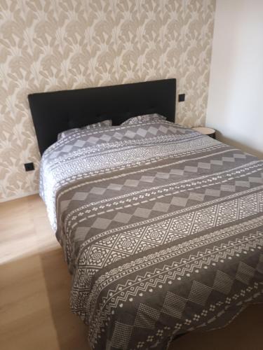 uma cama com um edredão preto e branco num quarto em Chez David - T2 neuf dans centre historique em Brioude