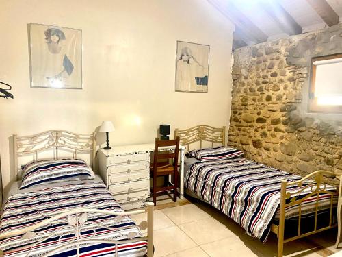 a bedroom with two beds and a stone wall at Domaine de Berducq in Monein