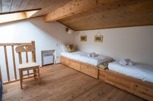 une chambre avec deux lits et une chaise dedans dans l'établissement Chalet Vorgeats 2 - 6 pers - Au pied de la Flégère - Golf - UTMB, à Chamonix-Mont-Blanc