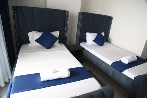 2 letti in una camera con cuscini bianchi e blu di Oceanview Vacation House in Mombasa Town Lenda Homes a Mombasa