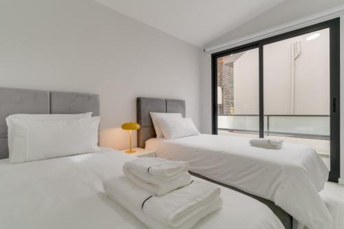 two white beds in a room with a window at Graça House in Machico