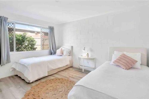 um quarto branco com 2 camas e uma janela em Island Villas - Lady Musgrave - Unit 1 em Bundaberg