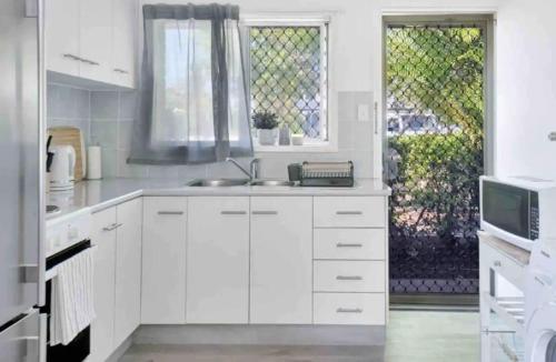 uma cozinha branca com um lavatório e uma janela em Island Villas - Lady Musgrave - Unit 1 em Bundaberg