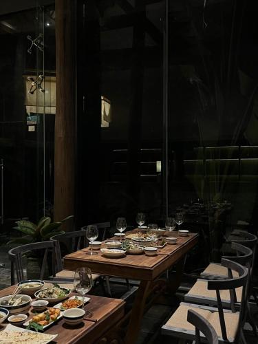 a wooden table with plates of food and wine glasses at TOKI Retreat Vân Long in Ninh Binh